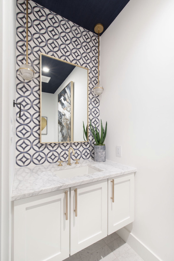 Mid-sized transitional powder room in Austin with shaker cabinets, white cabinets, a two-piece toilet, blue tile, white walls, marble floors, an undermount sink, white floor, white benchtops, a floating vanity and wallpaper.