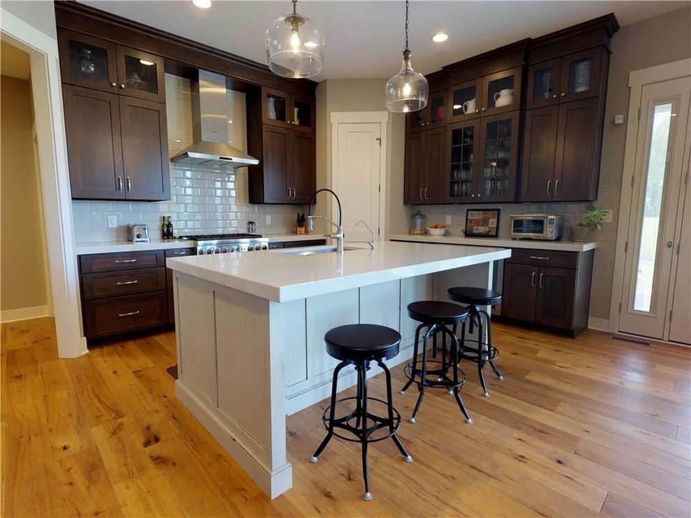Eat-in kitchen - transitional light wood floor eat-in kitchen idea in Indianapolis with an undermount sink, flat-panel cabinets, medium tone wood cabinets, quartz countertops, white backsplash, subway tile backsplash, stainless steel appliances and an island