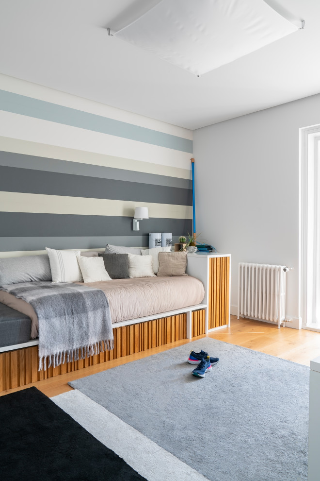 This is an example of a large gender-neutral kids' room in Other with grey walls, medium hardwood floors and wallpaper.