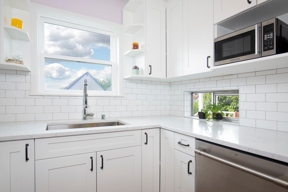 Inspiration for a small arts and crafts u-shaped separate kitchen in Seattle with an undermount sink, shaker cabinets, white cabinets, quartz benchtops, white splashback, ceramic splashback, stainless steel appliances, medium hardwood floors, no island, brown floor and white benchtop.