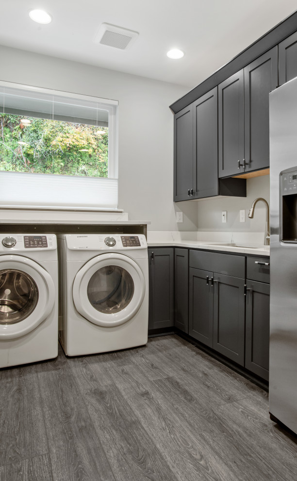 Design ideas for a large contemporary l-shaped utility room in Seattle with a drop-in sink, beaded inset cabinets, dark wood cabinets, marble benchtops, white splashback, white walls, vinyl floors, a side-by-side washer and dryer, grey floor, white benchtop and vaulted.