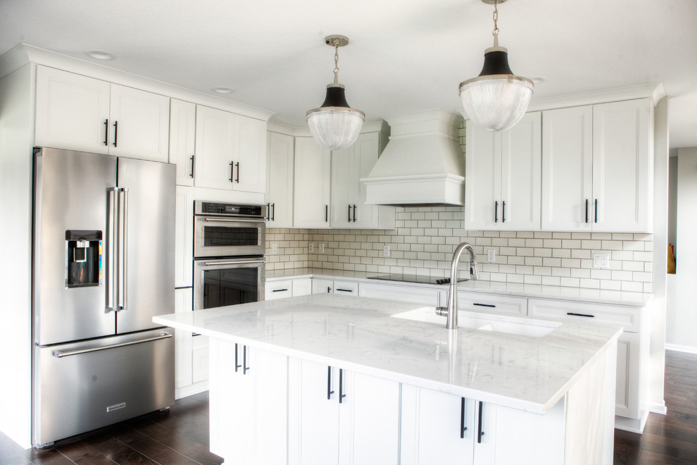 Inspiration for a large transitional l-shaped dark wood floor and brown floor eat-in kitchen remodel with an undermount sink, recessed-panel cabinets, white cabinets, quartz countertops, white backsplash, subway tile backsplash, stainless steel appliances and an island