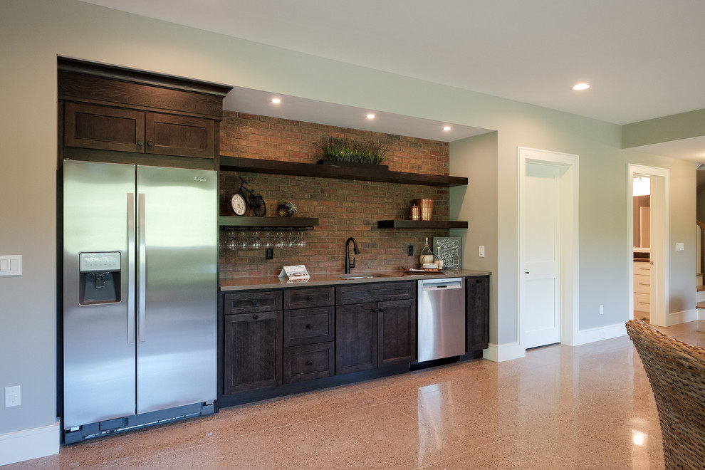 This is an example of a large arts and crafts single-wall wet bar in Grand Rapids with an undermount sink, recessed-panel cabinets, dark wood cabinets, quartz benchtops, red splashback, brick splashback, concrete floors and brown floor.