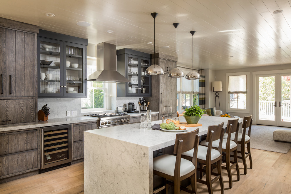 Inspiration for a transitional galley open plan kitchen in San Francisco with an undermount sink, flat-panel cabinets, dark wood cabinets, white splashback, stainless steel appliances, medium hardwood floors, with island, brown floor and white benchtop.