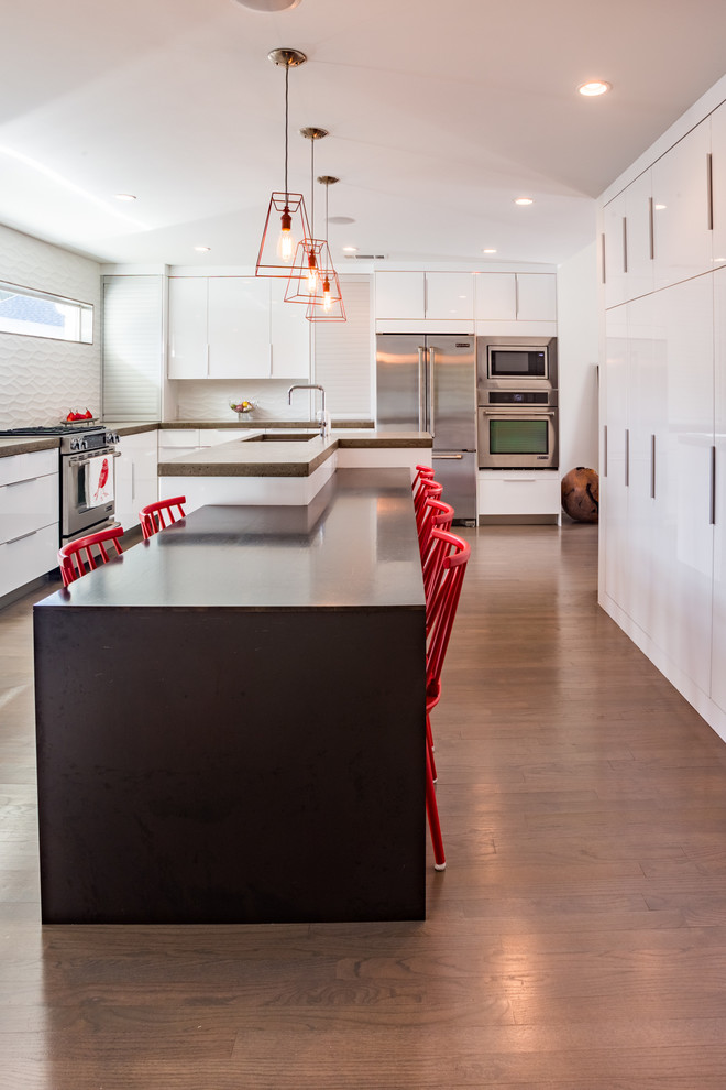 Contemporary kitchen in Dallas with an undermount sink, flat-panel cabinets, white cabinets, white splashback, porcelain splashback, stainless steel appliances and light hardwood floors.