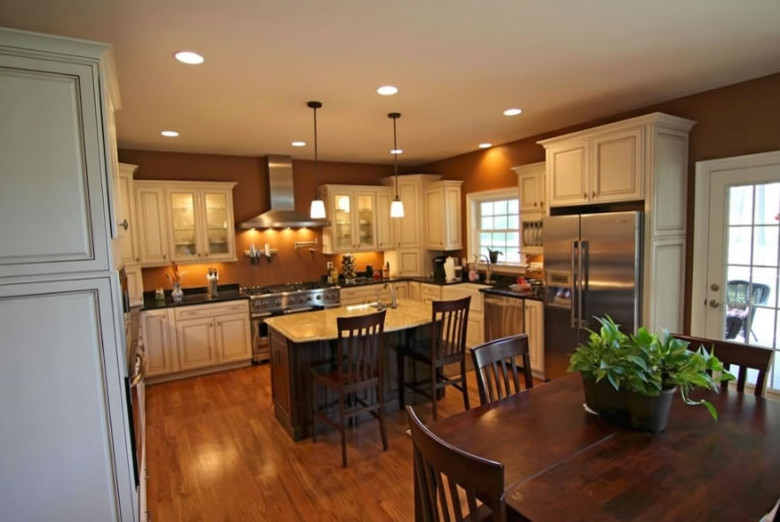 Photo of a large traditional u-shaped eat-in kitchen in Richmond with raised-panel cabinets, beige cabinets, granite benchtops, stainless steel appliances, medium hardwood floors and with island.