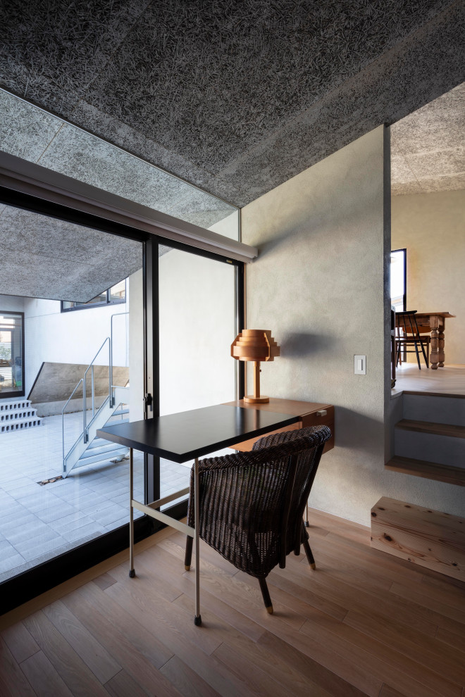 Diseño de despacho gris nórdico grande sin chimenea con paredes beige, suelo de madera clara, escritorio independiente, suelo beige, bandeja y machihembrado