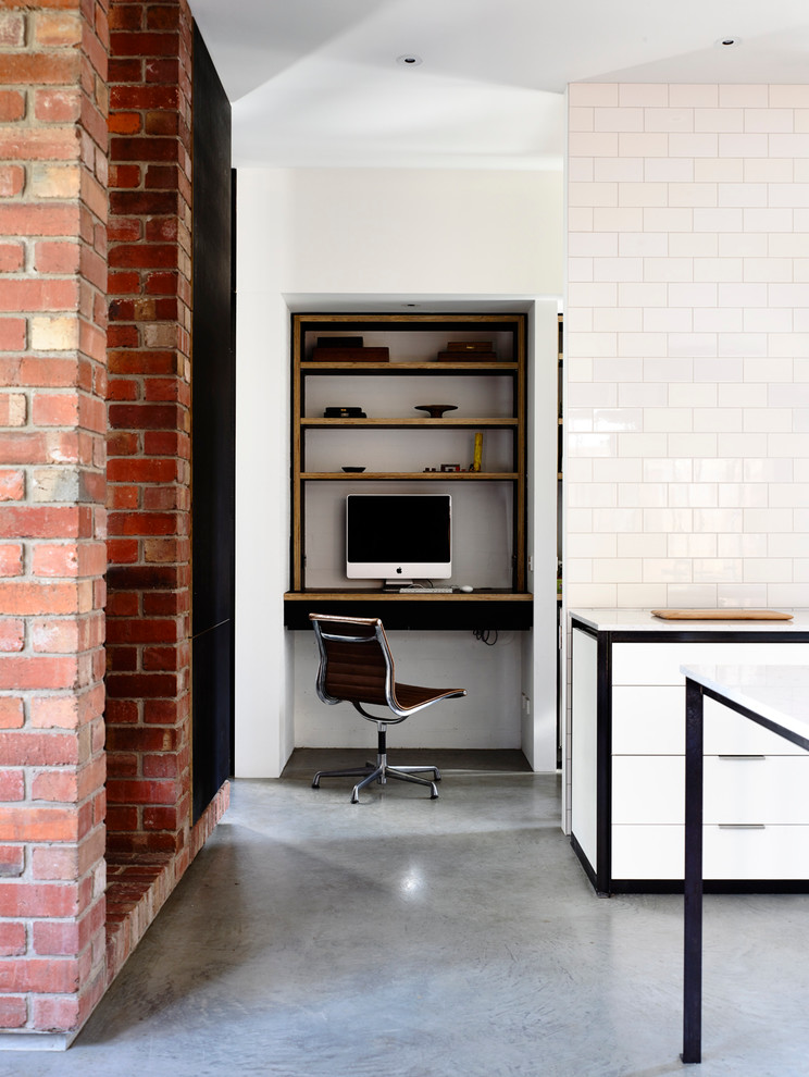 This is an example of a mid-sized contemporary galley eat-in kitchen in Melbourne with an undermount sink, flat-panel cabinets, white cabinets, quartz benchtops, white splashback, subway tile splashback, stainless steel appliances, concrete floors and with island.