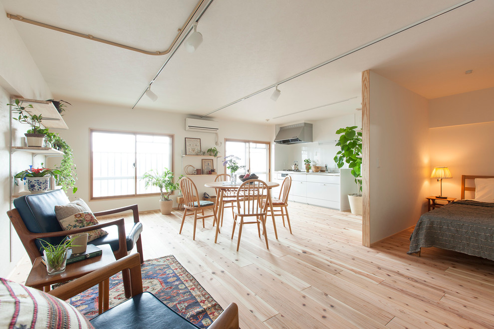 This is an example of an asian open concept living room in Tokyo with white walls, light hardwood floors and no fireplace.