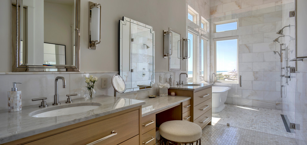 This is an example of a large beach style master wet room bathroom in Other with furniture-like cabinets, brown cabinets, a freestanding tub, a one-piece toilet, white walls, a drop-in sink, marble benchtops, a hinged shower door, grey benchtops, a double vanity, a built-in vanity, white tile, marble, mosaic tile floors and grey floor.