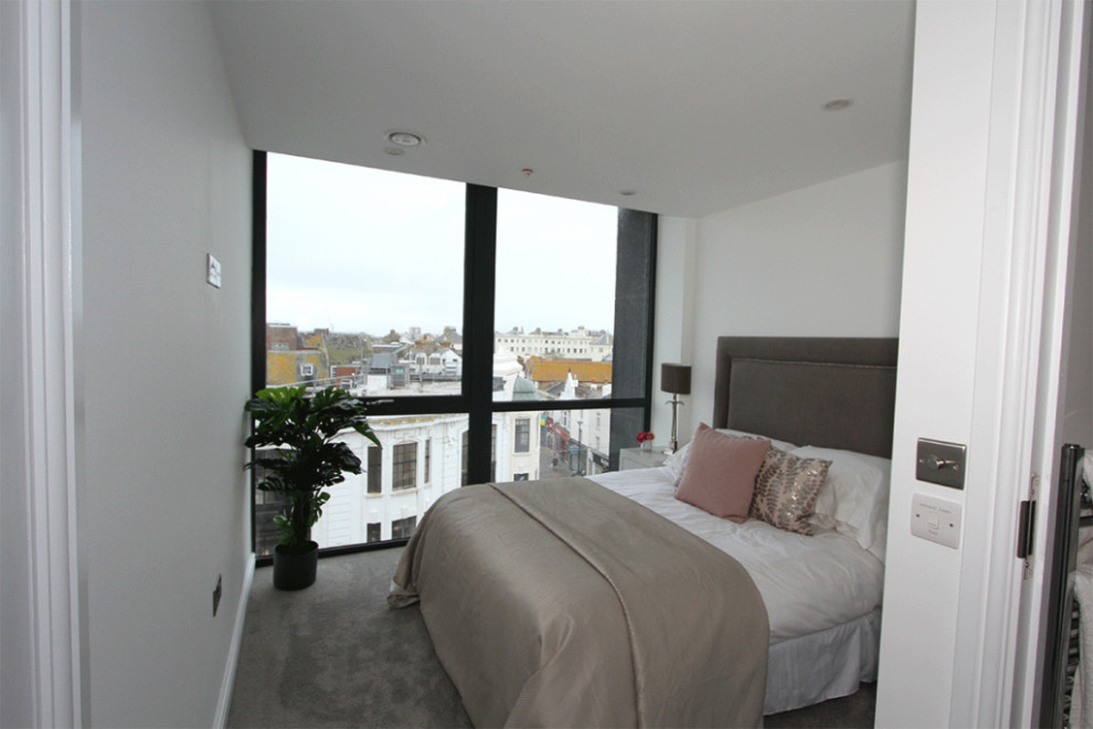 Modelo de dormitorio principal y gris y blanco moderno pequeño con paredes blancas, moqueta y suelo beige