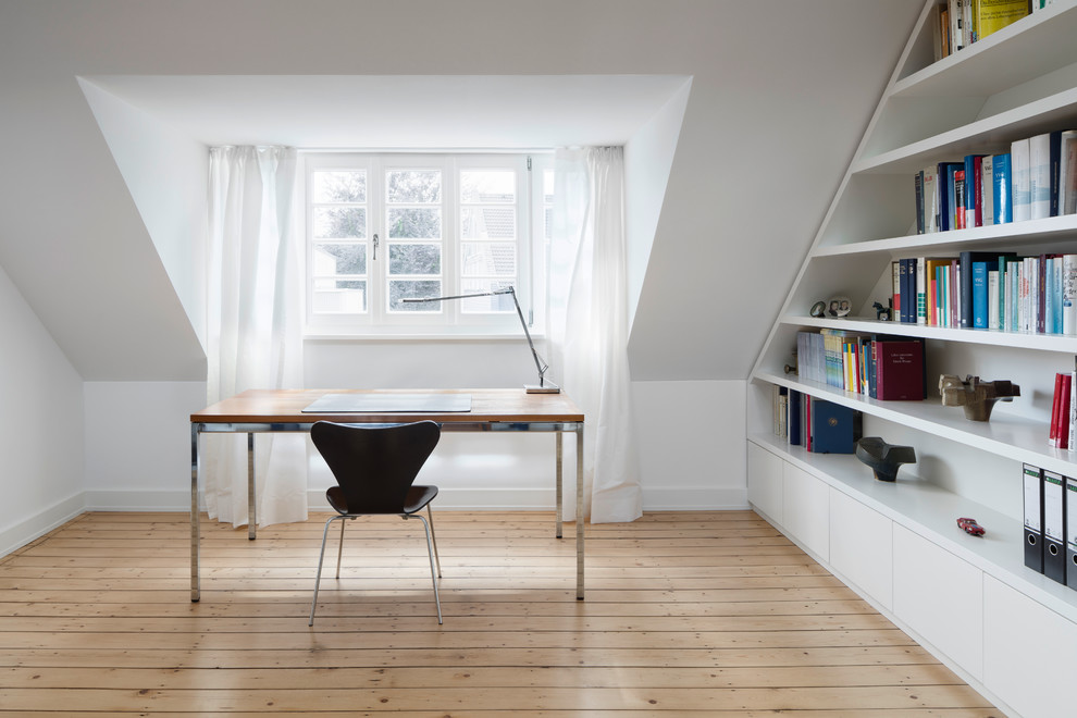 Inspiration for a mid-sized modern study room in Cologne with white walls, light hardwood floors and a freestanding desk.