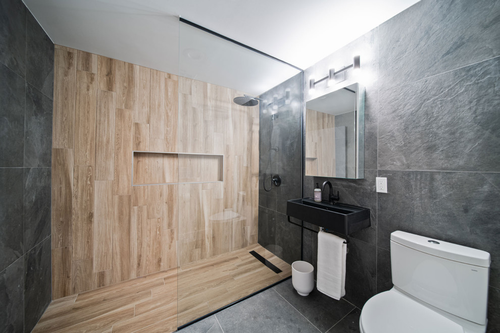 Photo of a mid-sized contemporary master bathroom in New York with black cabinets, a two-piece toilet, gray tile, a wall-mount sink, a single vanity and a floating vanity.