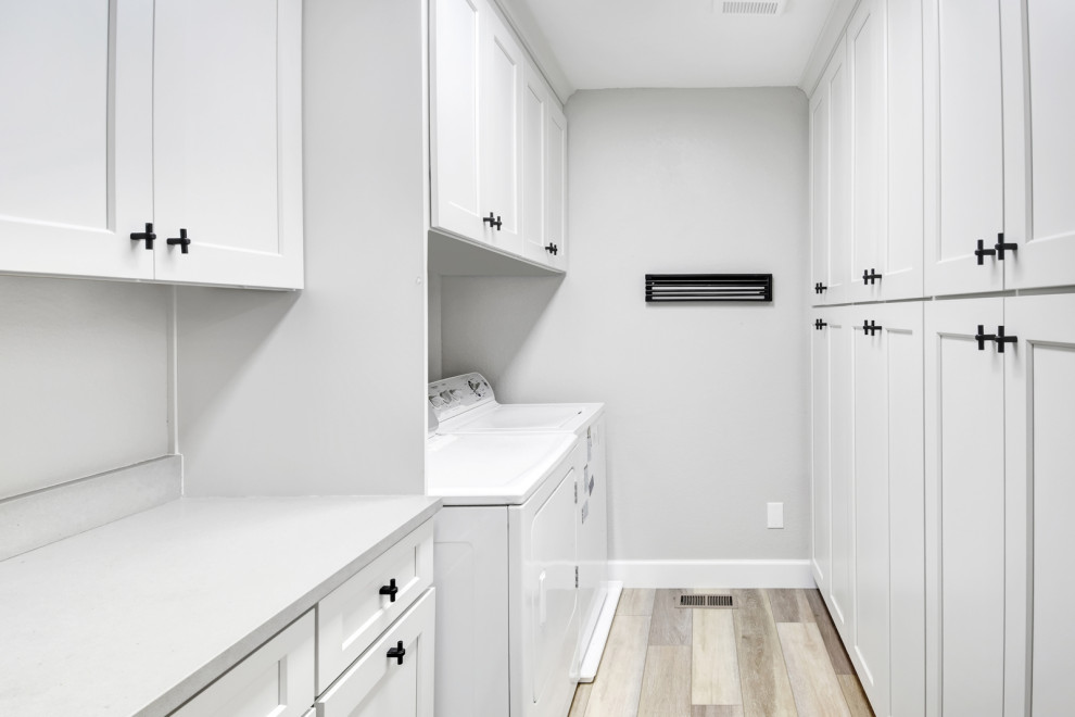 Idee per una lavanderia multiuso minimalista di medie dimensioni con ante in stile shaker, ante bianche, top in laminato, pavimento in laminato, pavimento marrone e top bianco