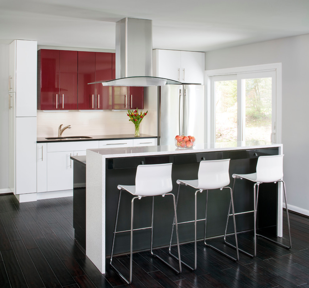 This is an example of a small contemporary galley eat-in kitchen in DC Metro with flat-panel cabinets, white splashback, dark hardwood floors, with island, an undermount sink, stainless steel appliances, solid surface benchtops and ceramic splashback.