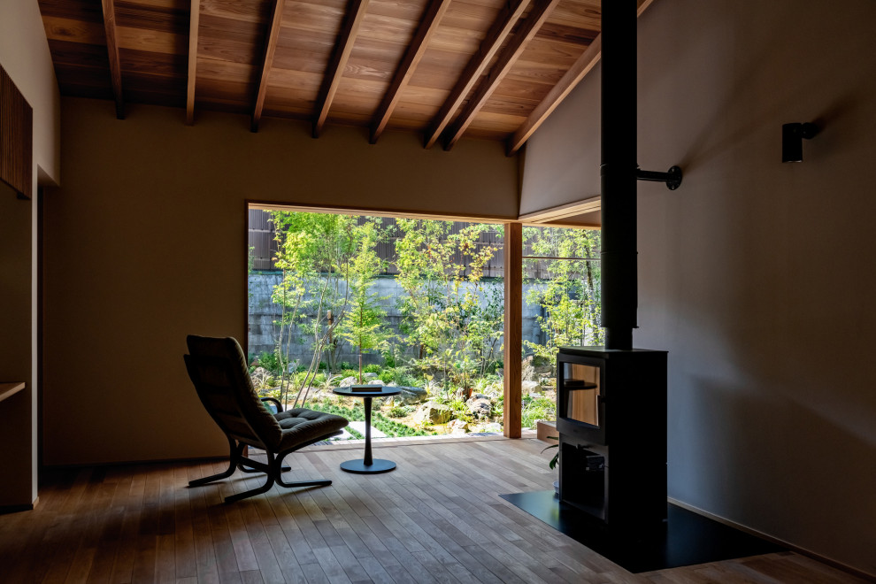 Foto de salón abierto grande con paredes grises, suelo de madera clara, estufa de leña, marco de chimenea de yeso y madera