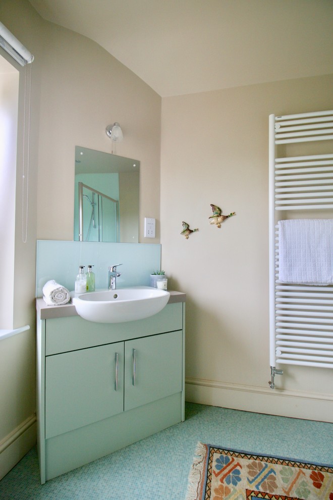 This is an example of a small traditional 3/4 bathroom in Other with flat-panel cabinets, green cabinets, an open shower, a one-piece toilet, green tile, glass sheet wall, beige walls, vinyl floors, a drop-in sink, laminate benchtops, green floor, a sliding shower screen and grey benchtops.