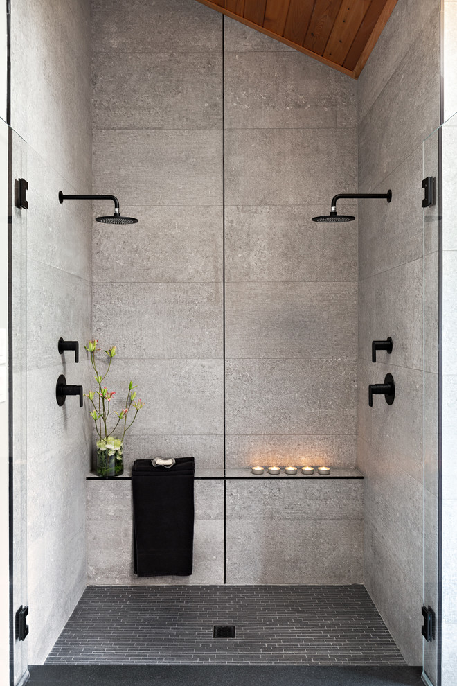 Photo of a large contemporary master bathroom in Other with a double shower, gray tile, grey walls, grey floor, a hinged shower door, medium wood cabinets, cement tile, concrete floors, a vessel sink, concrete benchtops and black benchtops.