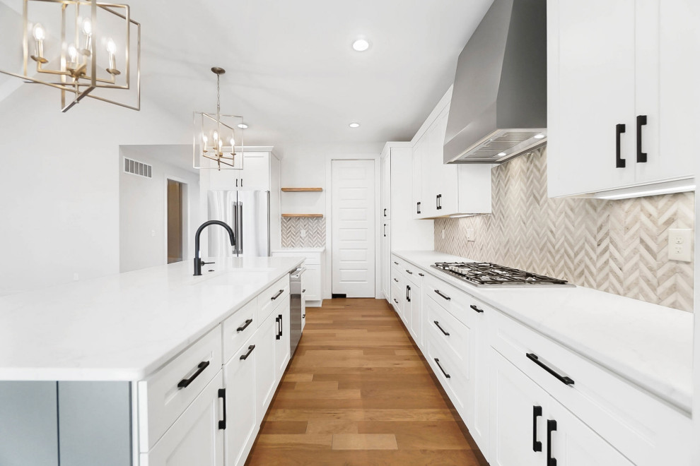 Mid-sized transitional l-shaped medium tone wood floor kitchen photo in Cincinnati with an undermount sink, shaker cabinets, white cabinets, quartzite countertops, mosaic tile backsplash, stainless steel appliances, an island and white countertops
