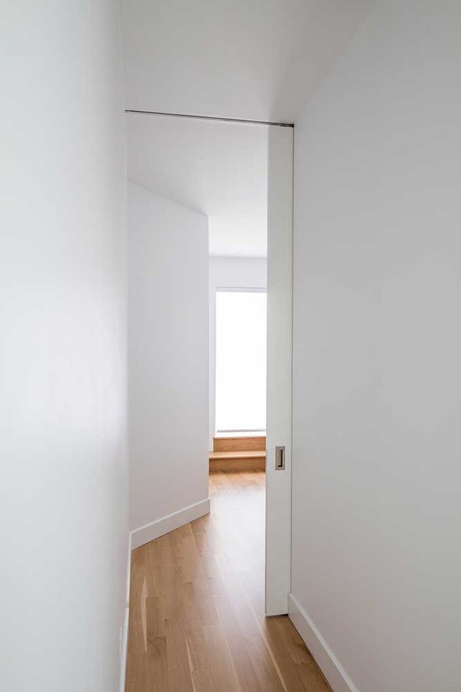 Design ideas for a mid-sized contemporary hallway in Montreal with white walls and medium hardwood floors.