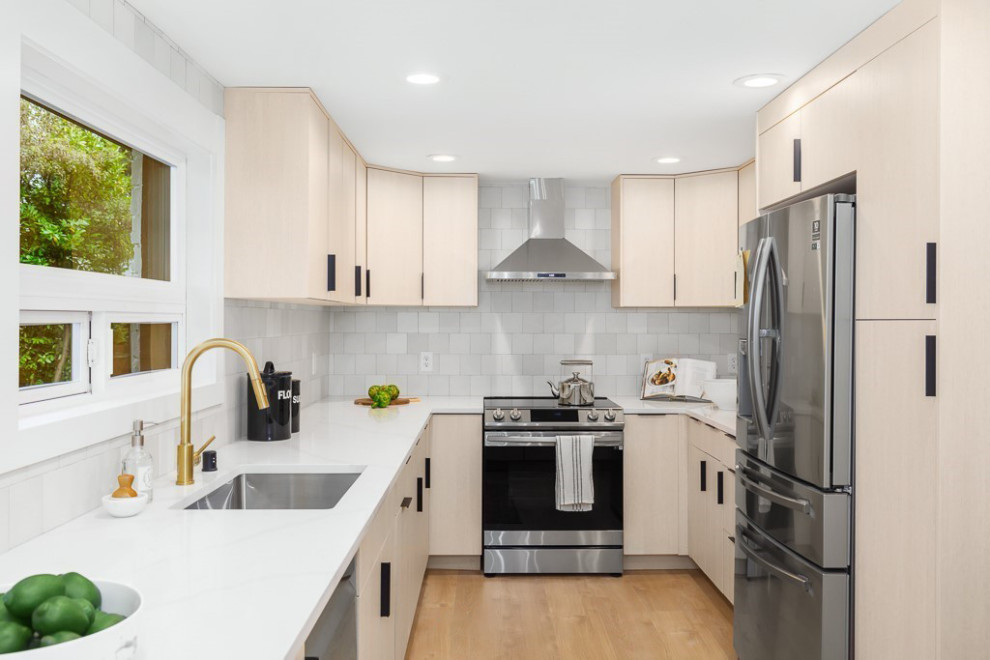 Design ideas for a transitional u-shaped separate kitchen in Seattle with an undermount sink, flat-panel cabinets, light wood cabinets, quartz benchtops, white splashback, porcelain splashback, stainless steel appliances, medium hardwood floors, a peninsula, brown floor and white benchtop.