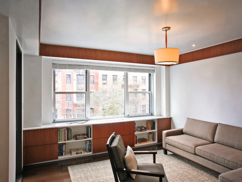 This is an example of a contemporary living room in New York with a library and white walls.