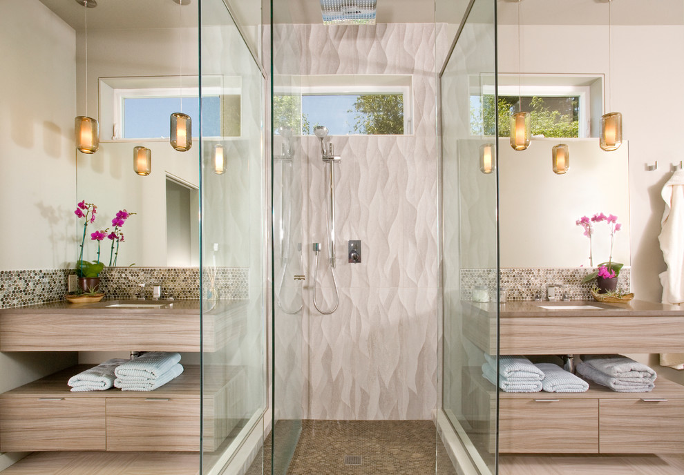 This is an example of a large contemporary master bathroom in Seattle with an undermount sink, flat-panel cabinets, light wood cabinets, an alcove shower, beige tile, mosaic tile, a freestanding tub, beige walls, solid surface benchtops and vinyl floors.