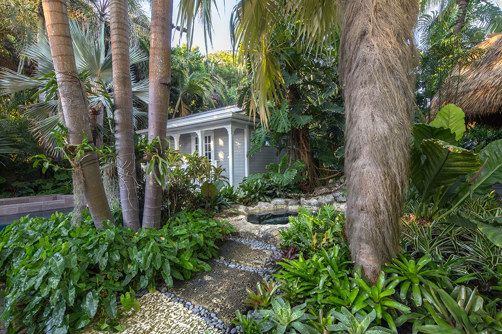 Design ideas for a mid-sized tropical side yard garden in Miami with natural stone pavers.