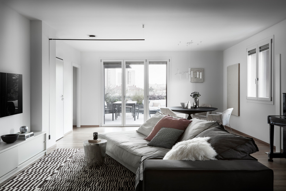 Idee per un grande soggiorno minimalista stile loft con sala della musica, pareti bianche, parquet chiaro e TV a parete