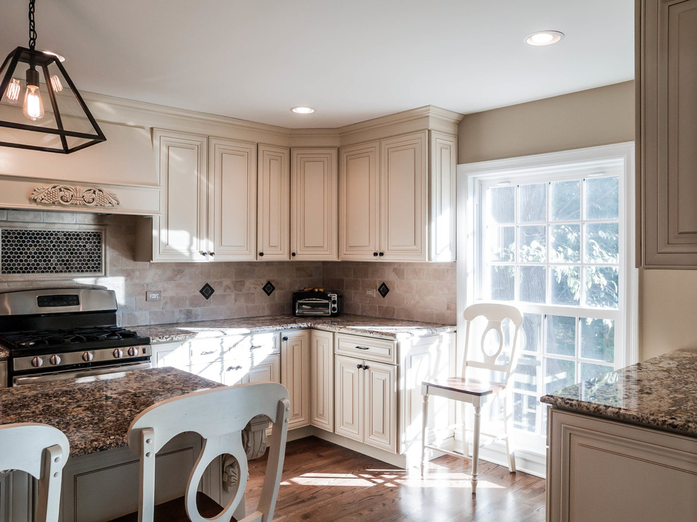 Design ideas for a traditional l-shaped separate kitchen in Chicago with an undermount sink, raised-panel cabinets, beige cabinets, granite benchtops, brown splashback and stainless steel appliances.