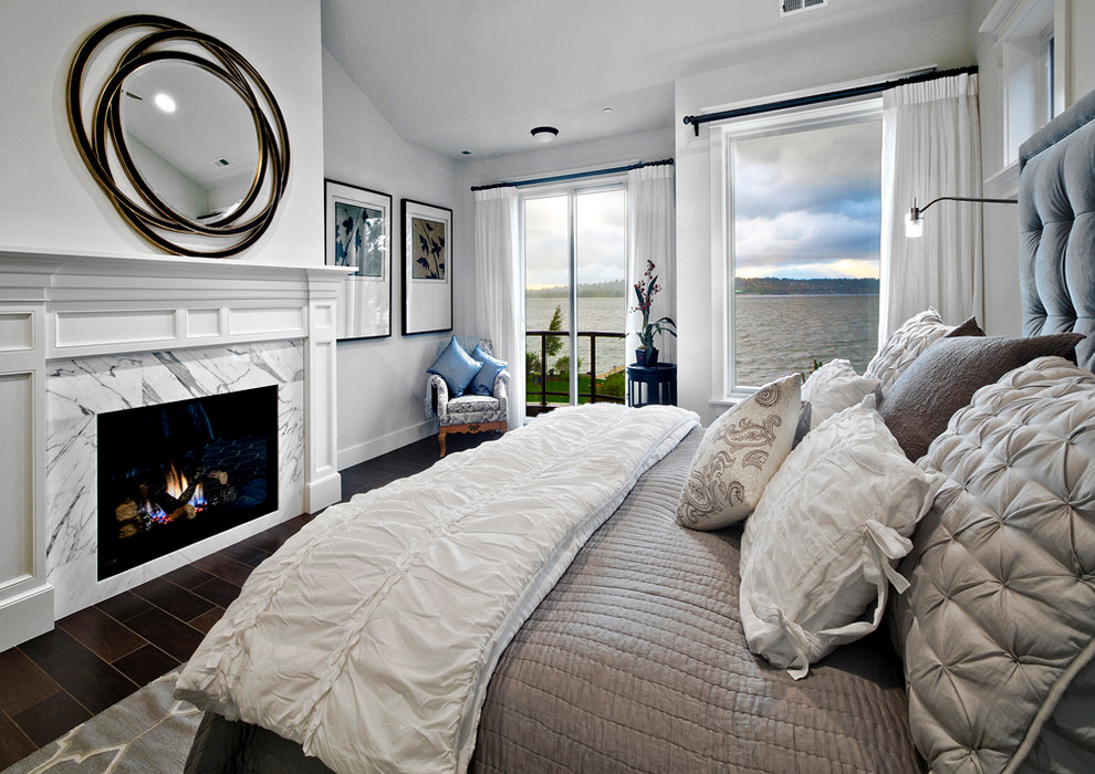 This is an example of a mid-sized transitional master bedroom in Seattle with grey walls, dark hardwood floors, a standard fireplace, a stone fireplace surround and brown floor.