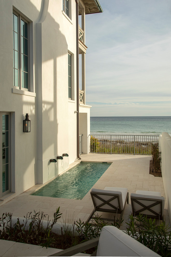 Inspiration for a small beach style side yard rectangular pool in Tampa with a water feature and natural stone pavers.