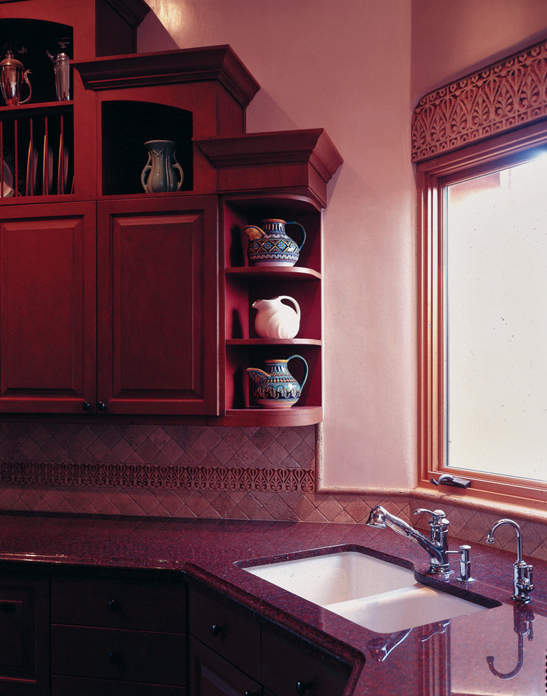 Mid-sized mediterranean u-shaped eat-in kitchen in Albuquerque with an undermount sink, raised-panel cabinets, medium wood cabinets, granite benchtops, beige splashback and stone tile splashback.