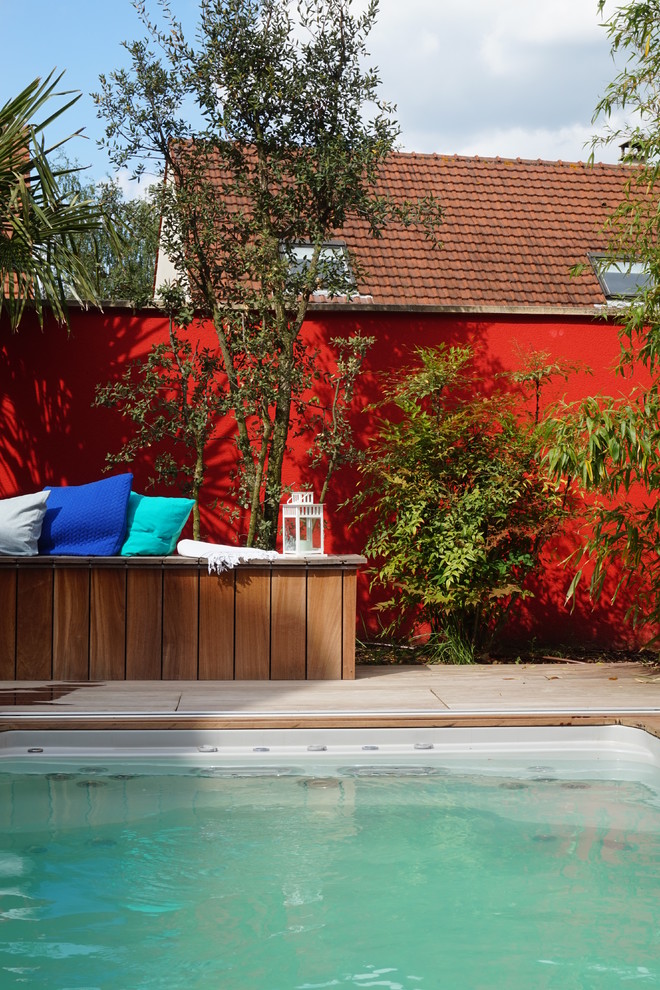 Design ideas for a mid-sized contemporary backyard pool in Paris with decking.