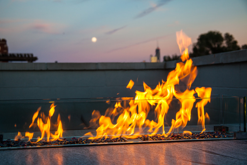 Photo of a mid-sized industrial rooftop deck in Chicago with a fire feature and an awning.