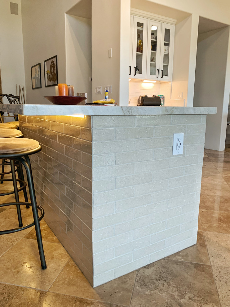 Photo of a large transitional l-shaped open plan kitchen in Phoenix with an undermount sink, raised-panel cabinets, white cabinets, granite benchtops, white splashback, ceramic splashback, stainless steel appliances, travertine floors, multiple islands, beige floor and beige benchtop.