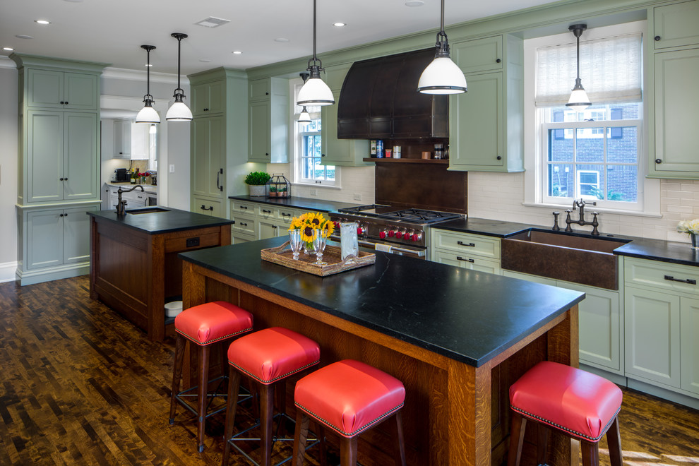 Inspiration for a large traditional galley open plan kitchen in Minneapolis with a farmhouse sink, green cabinets, quartzite benchtops, white splashback, subway tile splashback, panelled appliances, multiple islands, recessed-panel cabinets and dark hardwood floors.