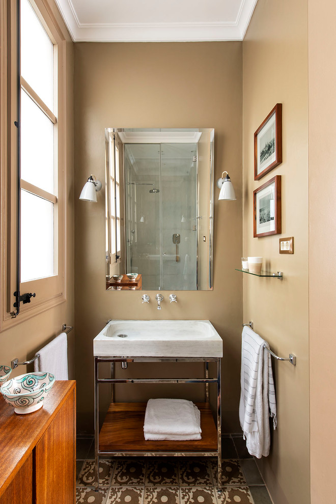 This is an example of a small transitional bathroom in Barcelona with open cabinets, brown walls, a console sink and brown floor.