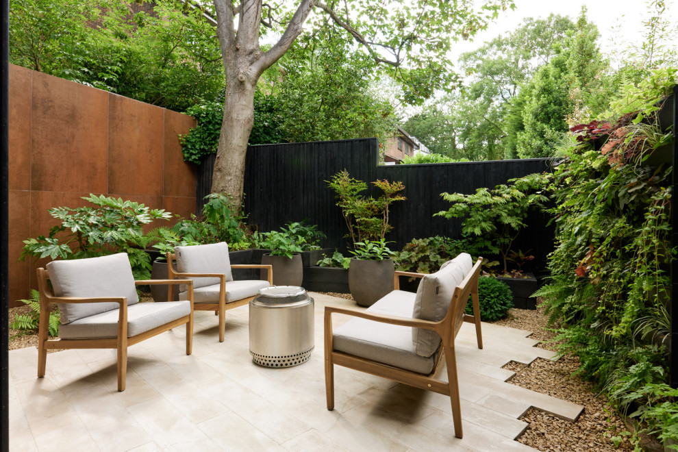 Cette image montre un petit jardin arrière minimaliste l'été avec une exposition partiellement ombragée, des pavés en pierre naturelle et une clôture en bois.