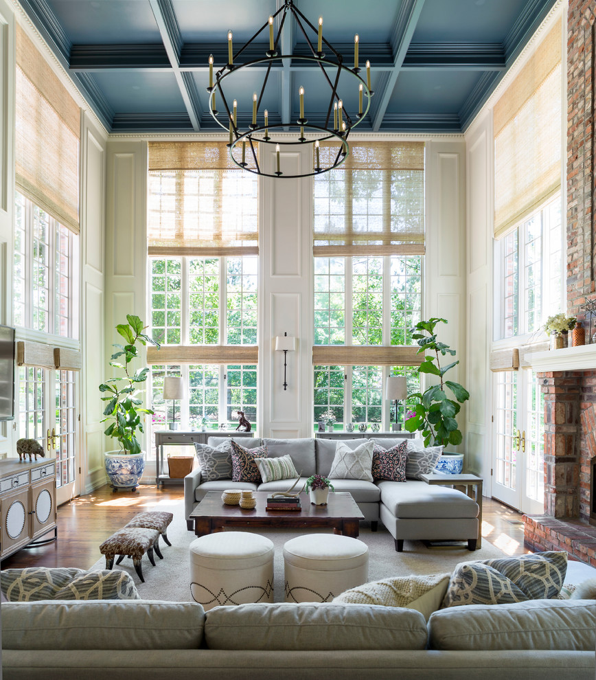 Inspiration for a huge timeless open concept medium tone wood floor and brown floor family room remodel in Denver with beige walls, a standard fireplace, a brick fireplace and a wall-mounted tv