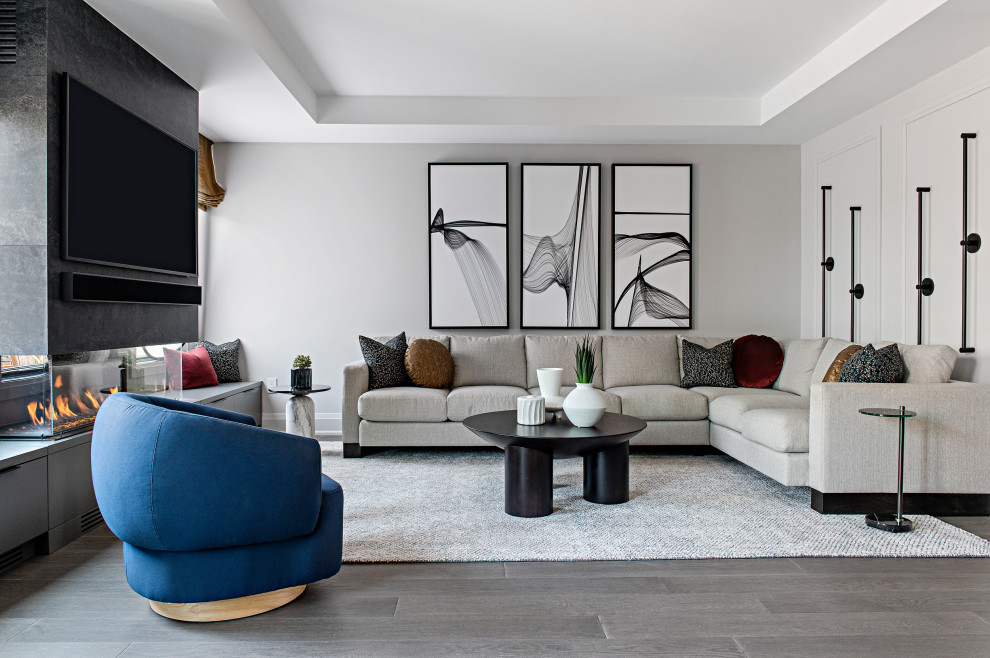 Mittelgroßes, Offenes Modernes Wohnzimmer mit grauer Wandfarbe, hellem Holzboden, Tunnelkamin, gefliester Kaminumrandung, TV-Wand, grauem Boden, eingelassener Decke und Wandpaneelen in Toronto