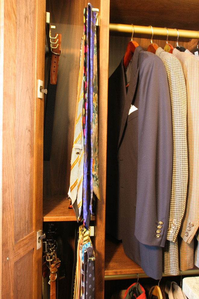 This is an example of a mid-sized traditional men's walk-in wardrobe in Louisville with raised-panel cabinets, medium wood cabinets, medium hardwood floors and brown floor.