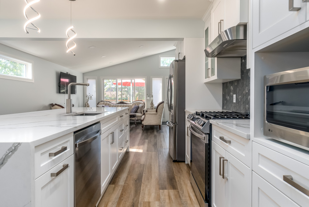 Inspiration for a transitional kitchen remodel in Edmonton with shaker cabinets, white cabinets, quartzite countertops, gray backsplash, cement tile backsplash, stainless steel appliances, an island and white countertops