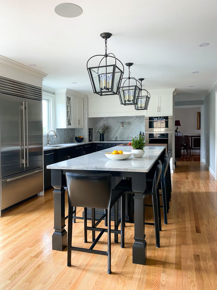 Photo of a transitional kitchen in Boston with an undermount sink, shaker cabinets, black cabinets, quartzite benchtops, grey splashback, stainless steel appliances, medium hardwood floors, with island and grey benchtop.