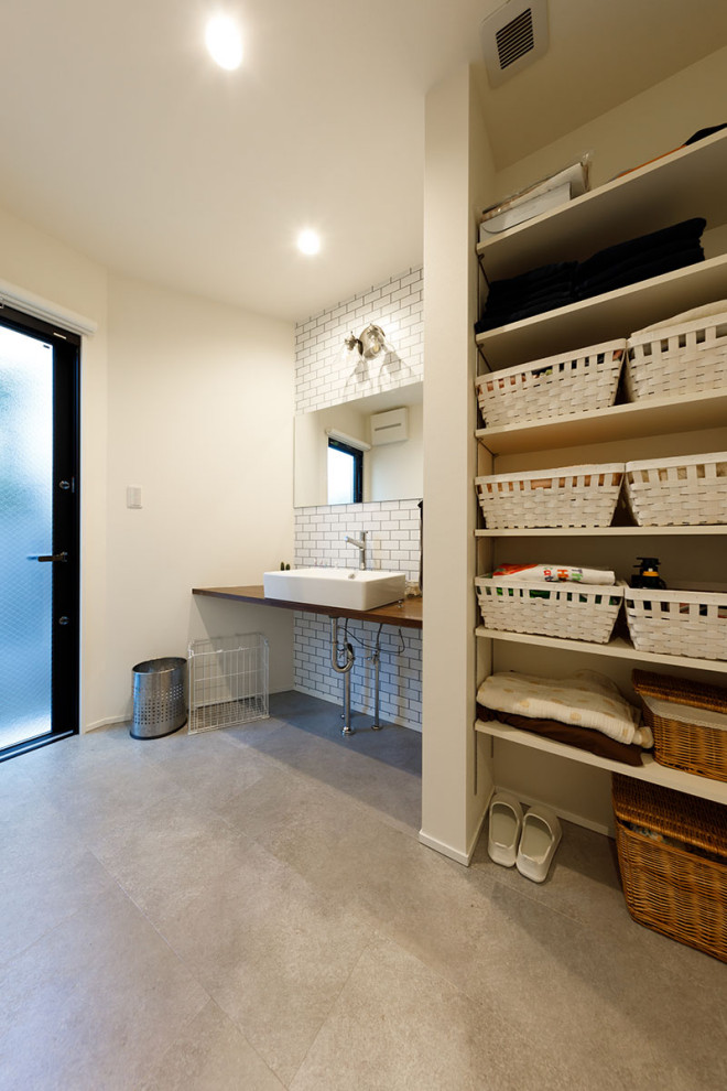 Mid-sized modern single-wall utility room in Tokyo Suburbs with a drop-in sink, beaded inset cabinets, white cabinets, solid surface benchtops, white walls, porcelain floors, grey floor, brown benchtop, wallpaper and wallpaper.
