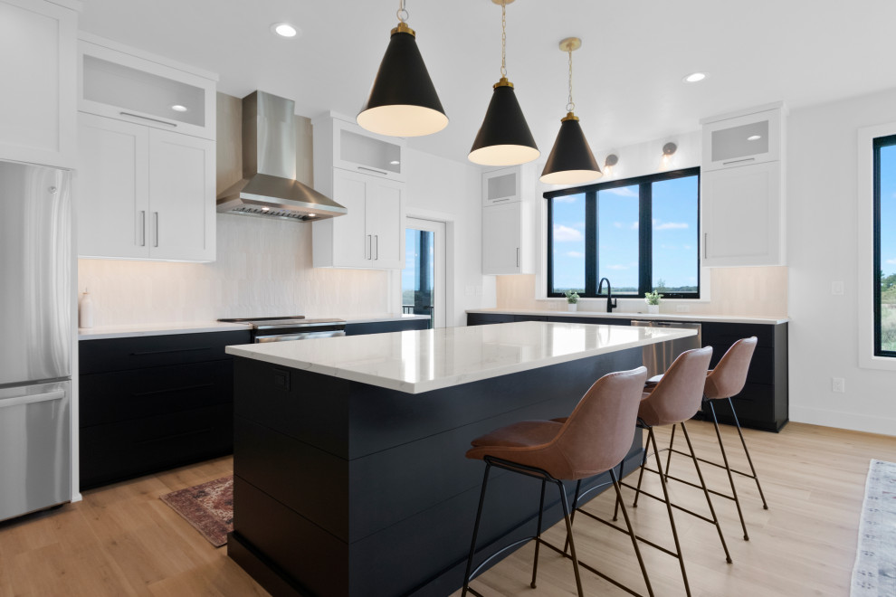 Eat-in kitchen - mid-sized l-shaped vinyl floor and brown floor eat-in kitchen idea with an undermount sink, shaker cabinets, white cabinets, quartz countertops, white backsplash, ceramic backsplash, stainless steel appliances, an island and white countertops