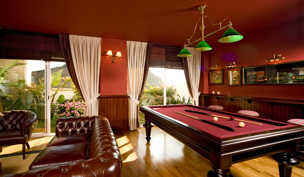 Photo of a large traditional enclosed family room in Madrid with red walls, medium hardwood floors, no fireplace and no tv.