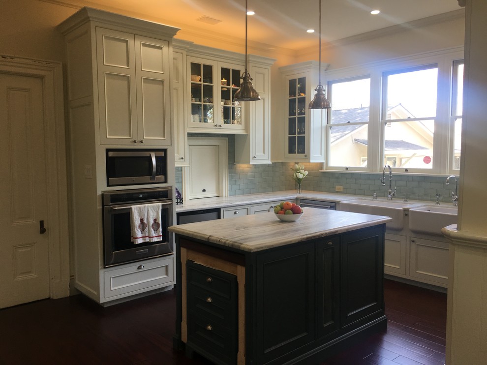 Photo of a large traditional u-shaped eat-in kitchen in Other with a farmhouse sink, recessed-panel cabinets, beige cabinets, quartzite benchtops, green splashback, subway tile splashback, stainless steel appliances, dark hardwood floors, with island, multi-coloured floor and multi-coloured benchtop.