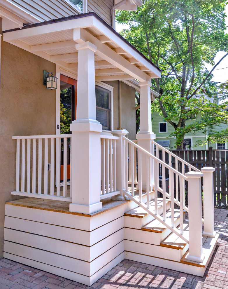 Cette image montre un porche d'entrée de maison arrière craftsman de taille moyenne avec des colonnes, des pavés en béton, une extension de toiture et un garde-corps en matériaux mixtes.