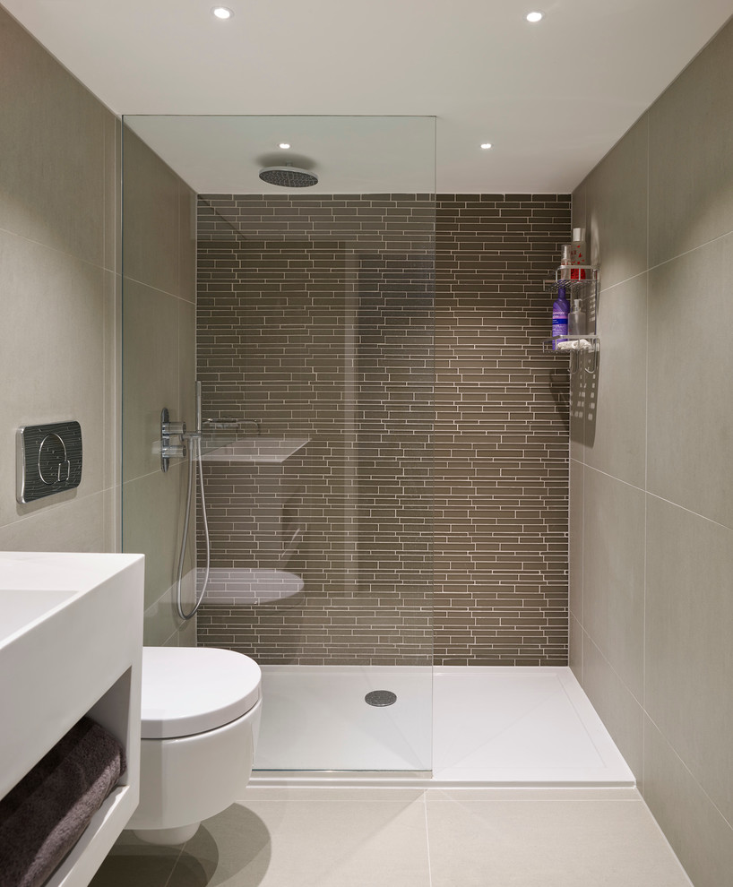 Photo of a contemporary master bathroom in London with an open shower, a wall-mount toilet, gray tile and glass tile.